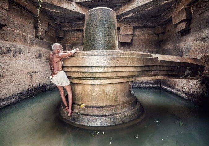 K.N. Krishna Bhat climbing the Shivlingam to perform priestly duties