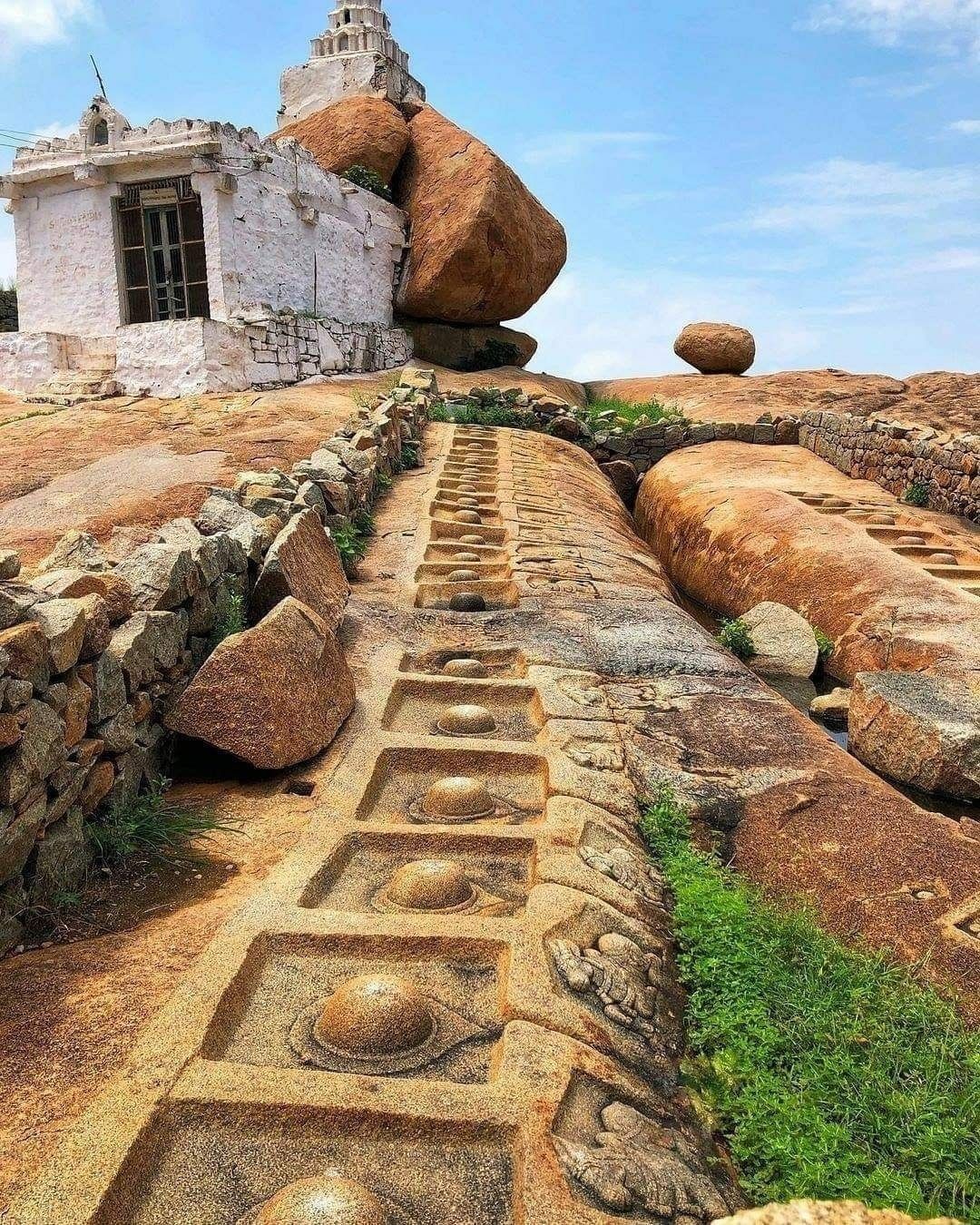 On the rocky floor, an array of carved Nandi (Bull) statues and Shiva Lingas