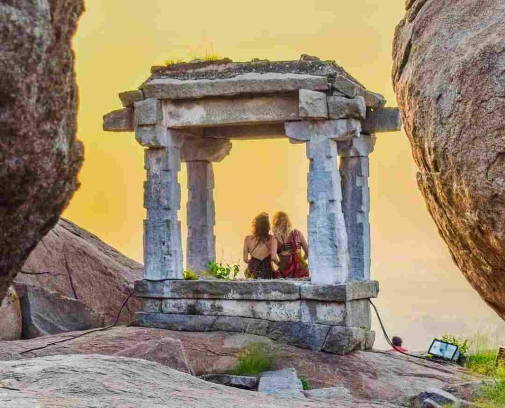 Two foreigners sit in a small pavilion, watching the sunset